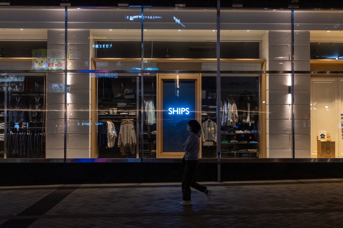 a man walking past a store front at night